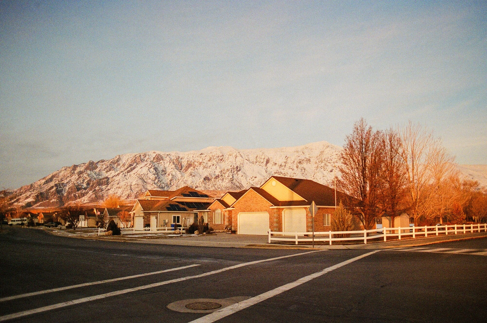 A quiet Utah street at sunrise below a snow-covered mountain ridge