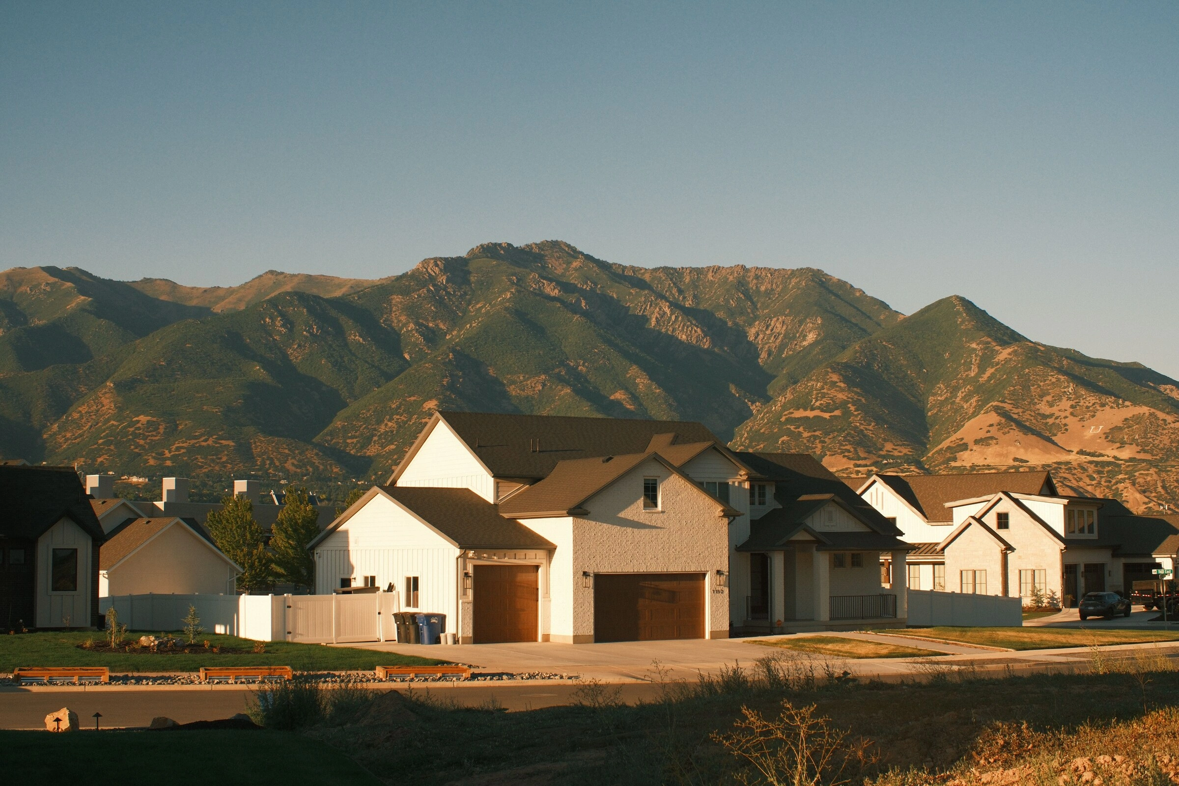 New homes glowing at sunset below a Utah mountain ridge