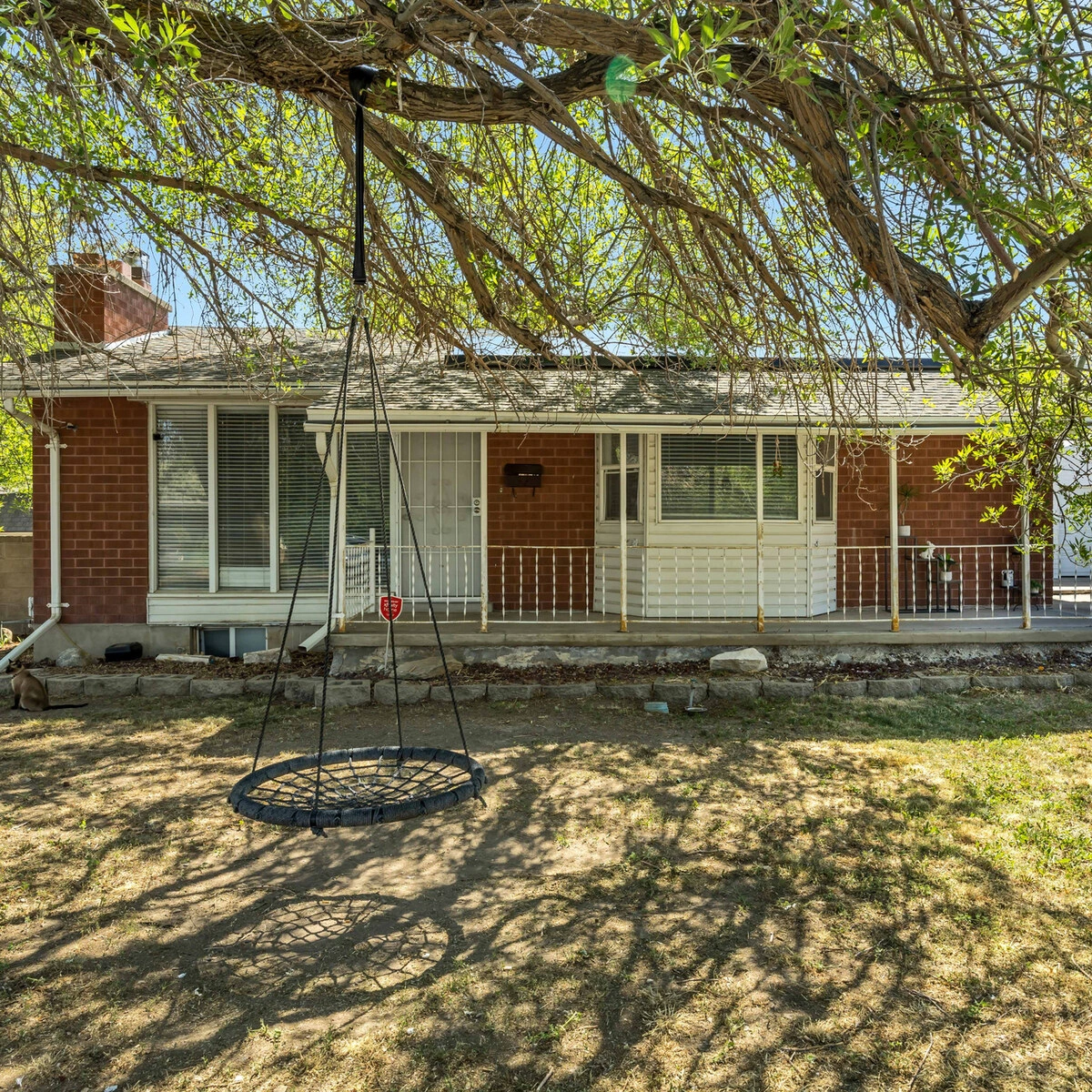 Brick rambler with a covered porch and a tree swing at 8435 W 3450 S, Magna