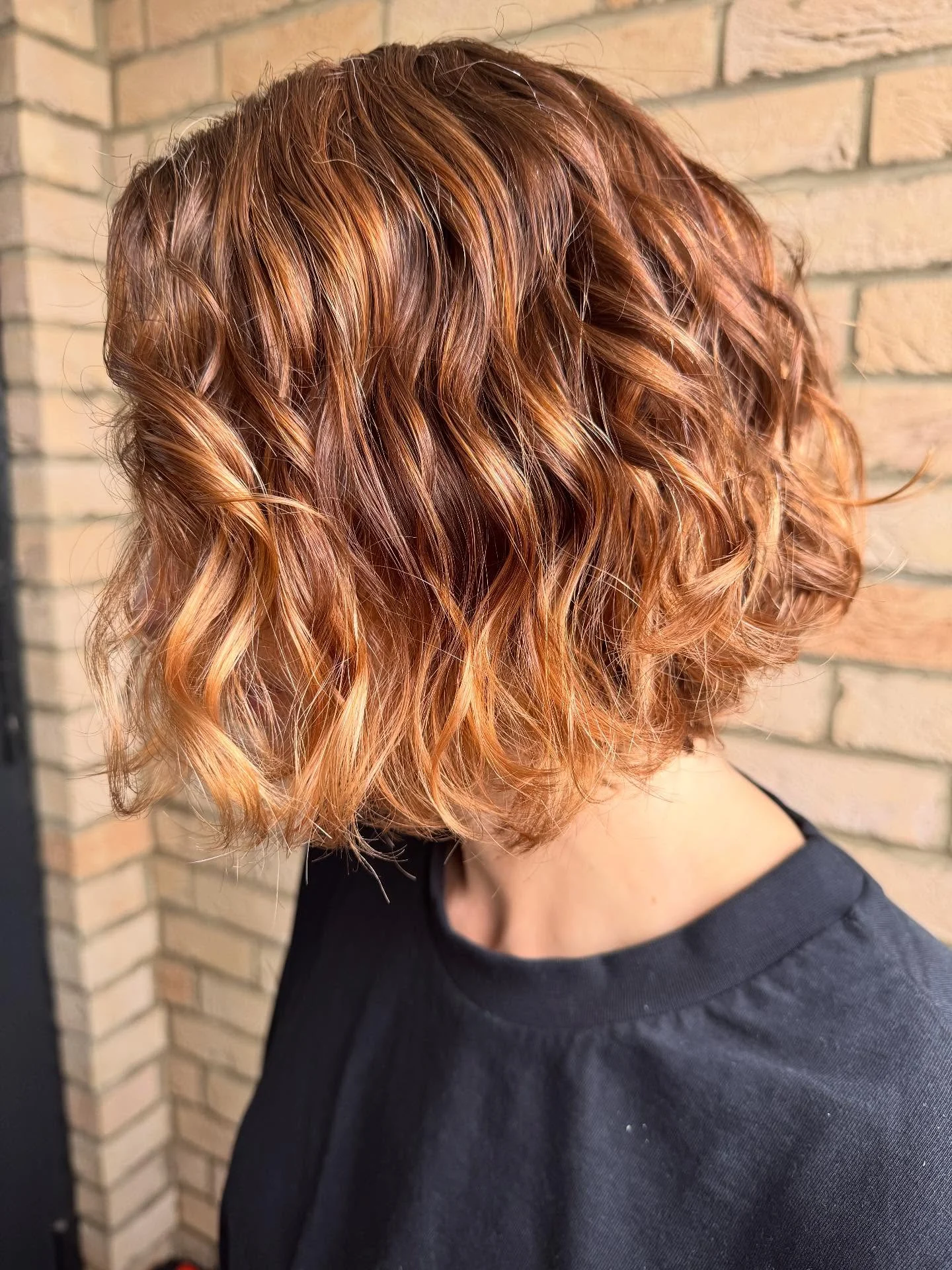 Short copper bob styled in defined, glossy waves