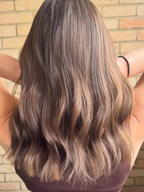 Dimensional brunette hair with soft waves and warm lived-in highlights