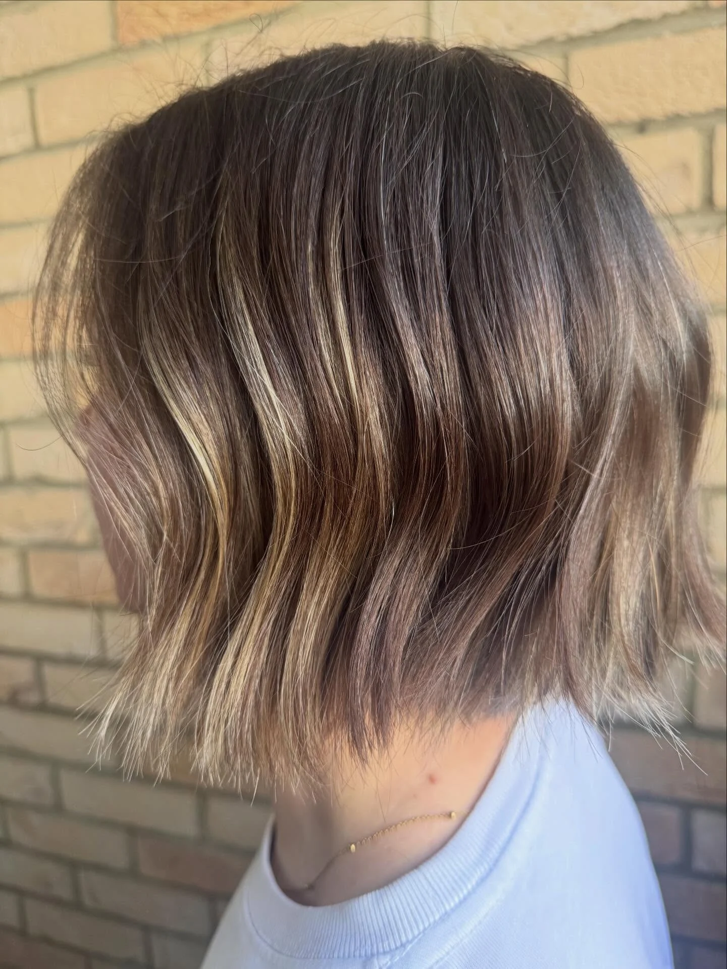 Short brunette bob with fine blonde ribbons and softly blended roots