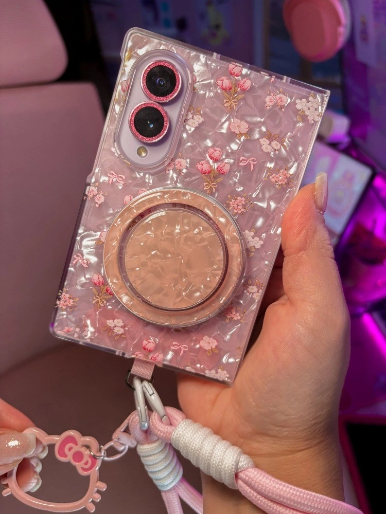 Galaxy Z Fold 8 in a pink glitter shell case with a rose gold grip and a Hello Kitty wrist strap