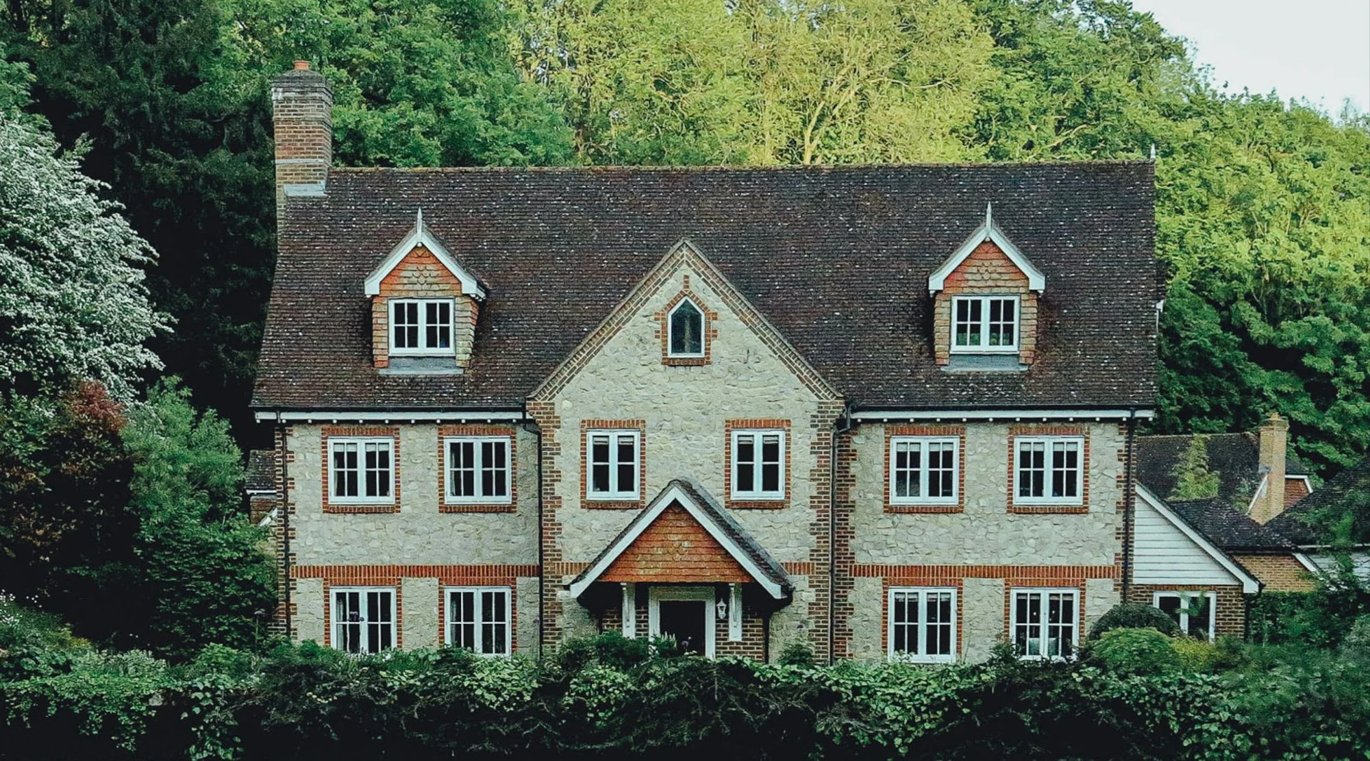 A welcoming stone home surrounded by mature trees