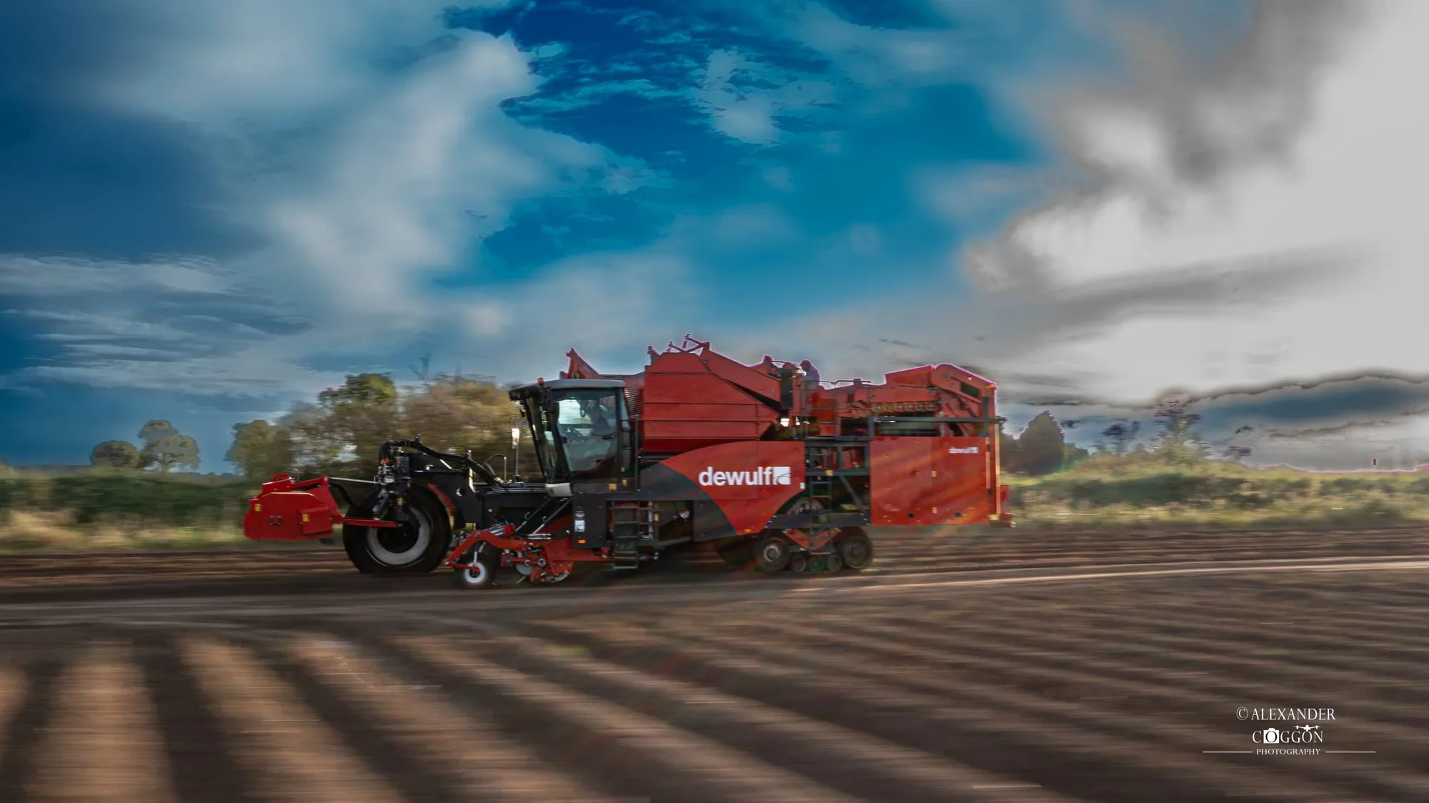 Red potato harvester working under a blue sky