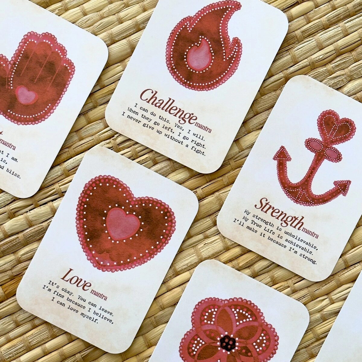 Mini Mantra Cards with red heart, anchor and flame illustrations on a woven mat