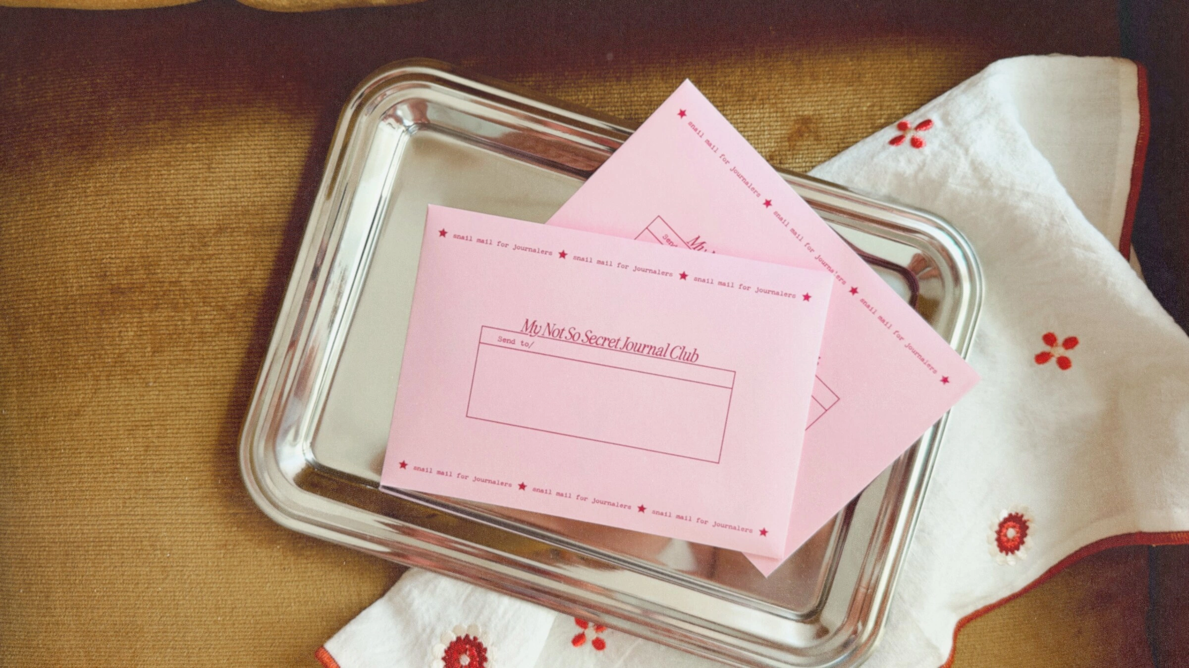 Two pink My Not So Secret Journal Club envelopes on a silver tray
