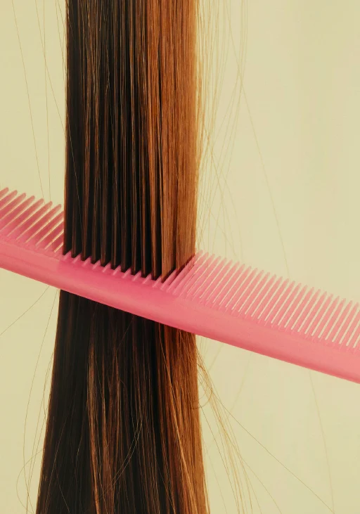 Hair being precisely cut with a bright pink comb