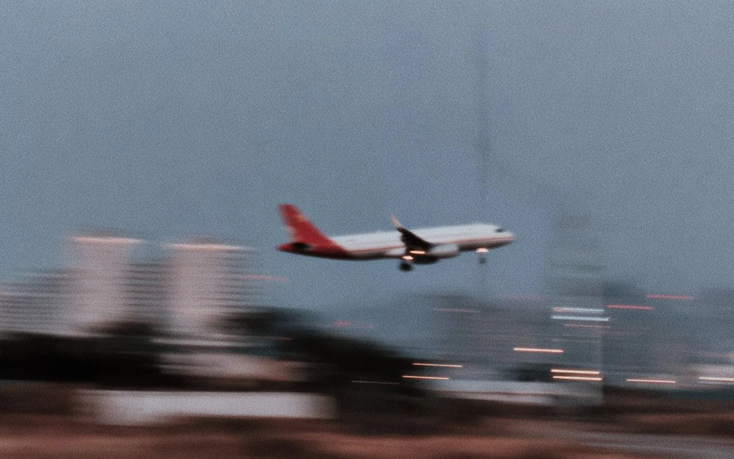 An airplane descending past a blurred city skyline