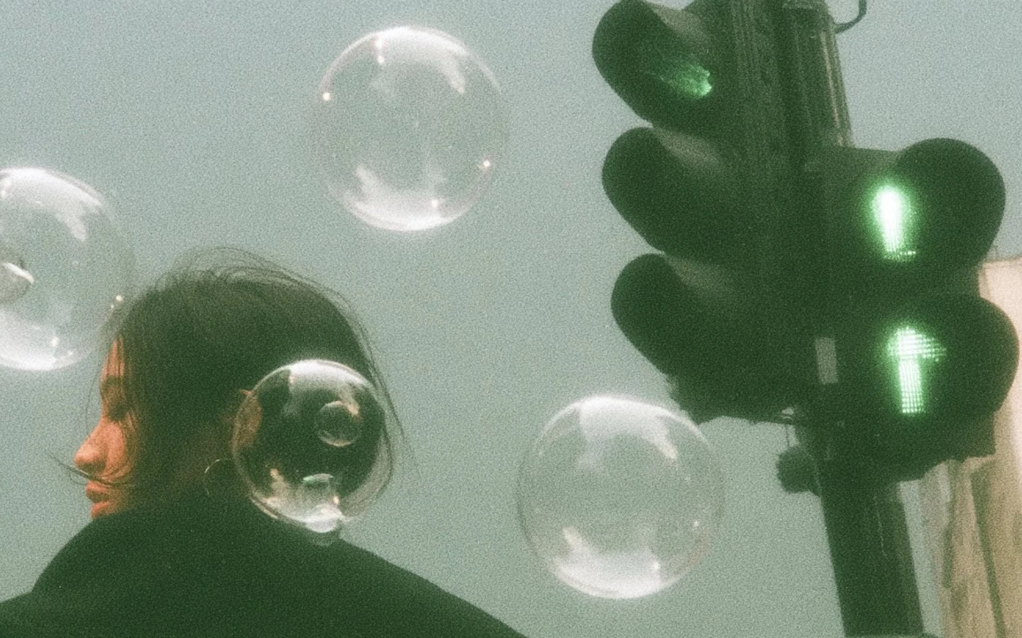A grainy street portrait framed by floating bubbles and a glowing green traffic light