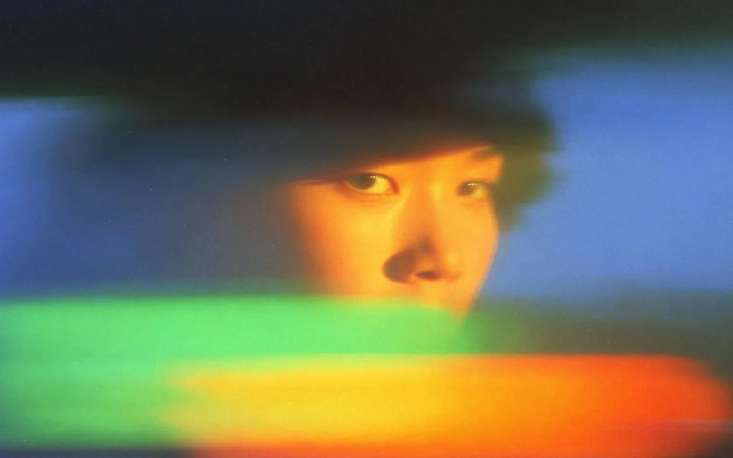 A softly focused portrait illuminated by bands of vivid color